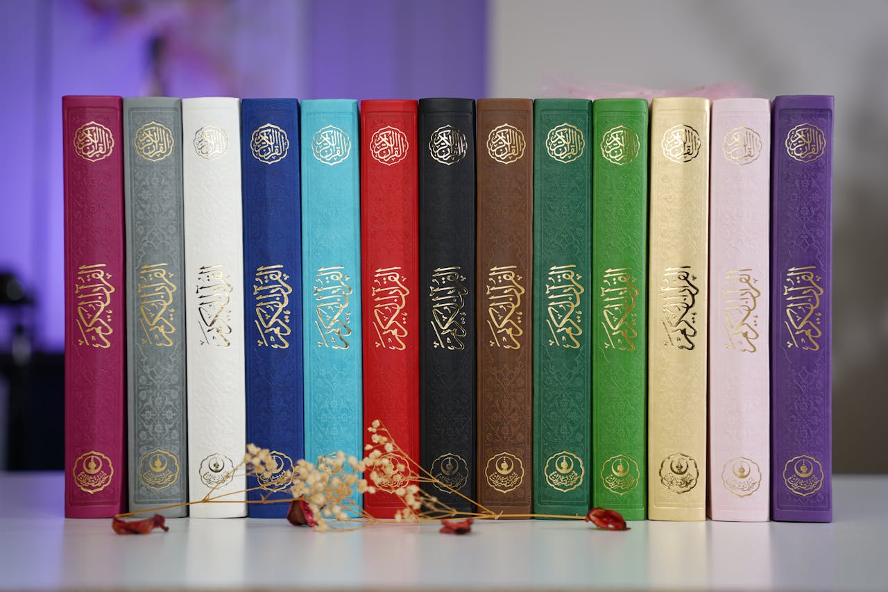 A vibrant array of Quran hardcover books in various colors displayed on a shelf indoors.